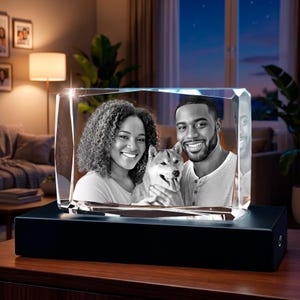 Peut inclure: Un bloc de verre rectangulaire présentant une photographie gravée au laser en noir et blanc d'une femme, d'un homme et d'un chien souriants. Le bloc de verre est monté sur une base rectangulaire noire solide servant de support.