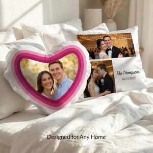 May include: A heart-shaped cushion featuring a photo of a couple framed by pink and magenta concentric rings, alongside a rectangular cushion displaying two wedding photos, the text The Thompsons, and the date 06/10/2025 on a white fabric.