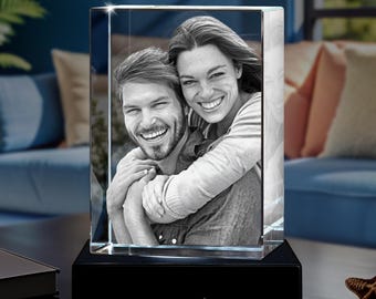 May include: A rectangular glass block featuring a laser-etched black and white photograph of two smiling people embracing. The glass block rests on a black rectangular base with the text ARTPIX printed in white on the front face of the base.