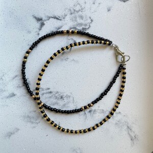 May include: A black and gold beaded bracelet with a clasp fastening.