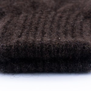 May include: Close-up of a dark brown knitted fabric with a fuzzy texture.