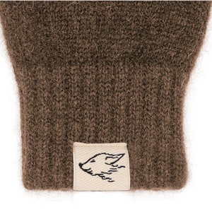 May include: Brown knitted gloves with a small white label featuring a black fox design.