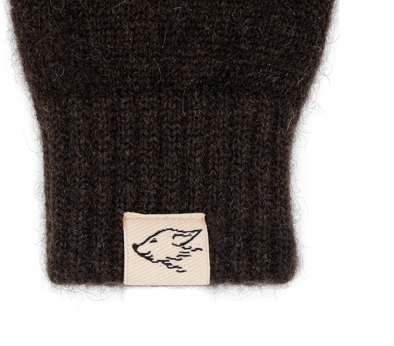 May include: A pair of brown knitted gloves with a small, cream-colored label featuring a black and white illustration of a fox's head.