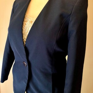 May include: A navy blue blazer with a single button closure and a v-neck.
