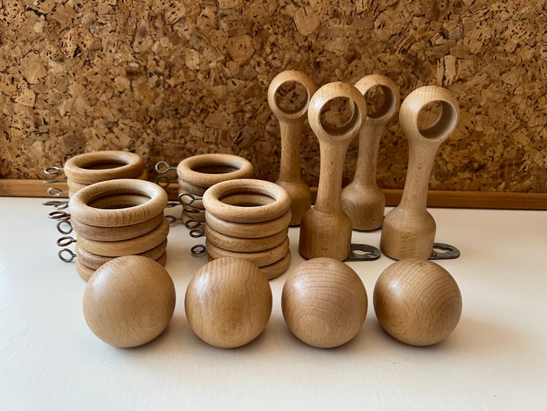 K&ouml;nnte beinhalten: Ein Satz aus Holz-Gardinenendst&uuml;cken und Ringen. Die Endst&uuml;cke sind rund und haben eine glatte Oberfl&auml;che. Die Ringe sind ebenfalls rund und haben eine glatte Oberfl&auml;che. Die Endst&uuml;cke und Ringe sind alle aus Naturholz.