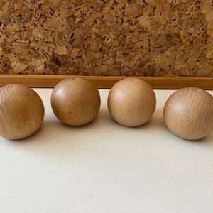 K&ouml;nnte beinhalten: Vier glatte, braune Holzb&auml;lle. Die B&auml;lle sind in einer Reihe auf einer wei&szlig;en Oberfl&auml;che angeordnet.