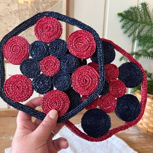 Peut inclure: Deux dessous-de-plat tissés avec un motif circulaire de cercles rouges et bleus. Les dessous-de-plat sont faits d'un matériau naturel et ont un aspect rustique.