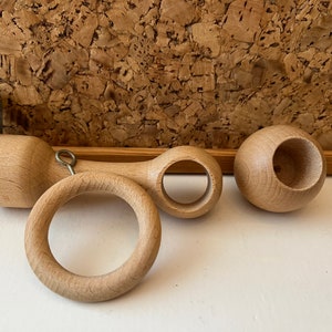 K&ouml;nnte beinhalten: Drei Gardinenstangen-Endst&uuml;cke aus Holz. Zwei sind rund mit einem Loch in der Mitte. Das dritte ist ein langes, zylindrisches St&uuml;ck mit einem Ring an einem Ende und einem Loch am anderen Ende.