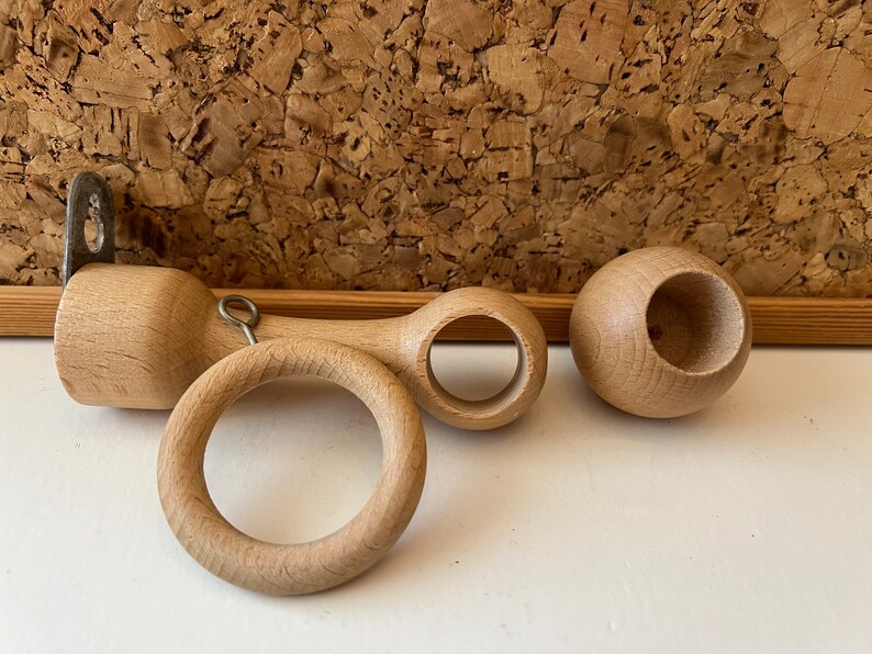 K&ouml;nnte beinhalten: Drei Gardinenstangen-Endst&uuml;cke aus Holz. Zwei sind rund mit einem Loch in der Mitte. Das dritte ist ein langes, zylindrisches St&uuml;ck mit einem Ring an einem Ende und einem Loch am anderen Ende.