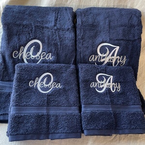 May include: Four navy blue towels with white embroidered lettering. Two towels have the name "Chelsea" embroidered on them, and two towels have the name "Anthony" embroidered on them.