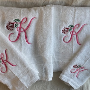 May include: Set of four white towels with pink embroidered roses and the letter K. The towels are different sizes.