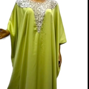 Puede incluir: Una kaftan verde lima con un escote de lentejuelas plateadas. La kaftan tiene un corte holgado y fluido, ideal para un look casual y veraniego.