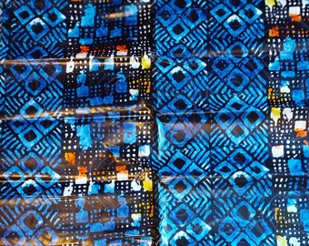 May include: A close-up of a fabric with a repeating geometric pattern. The design features blue, white, and orange shapes on a dark background. The pattern includes diamond and square shapes.
