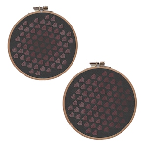 May include: Two round embroidery hoops with a dark gray fabric background. Each hoop features a pattern of pink hearts arranged in a gradient design. The wooden hoops are secured with metal clasps.