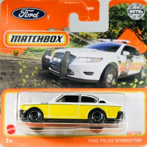 May include: A Matchbox Ford Police Interceptor toy car, model 42/100, in yellow and white. The packaging features the Ford logo and the Matchbox brand. The toy car is presented in a clear plastic case.