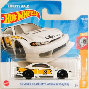 Może przedstawiać: Biały model samochodu Hot Wheels z odlewu ciśnieniowego z żółtymi akcentami. Samochód to Nissan Silvia S15 z pakietem bodykit Liberty Walk. Samochód ma numer 23 na boku i napis "LB Super Silhouette Nissan Silvia (S15)" na dole karty.
