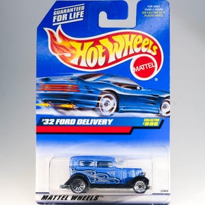 May include: A blue 1932 Ford Delivery Hot Wheels toy car in a blue and red collector's card with the text 'Guaranteed for Life' and 'Collector 1996'.