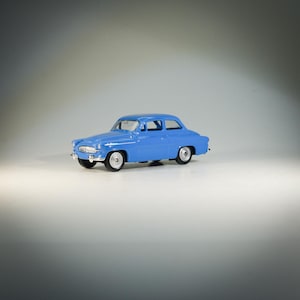 Peut inclure: Une voiture miniature bleue en forme de berline classique. La voiture a un intérieur blanc et des roues noires.
