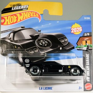 May include: A black Hot Wheels die-cast toy car, the "La Liebre" model, with silver wheels and a distinctive design. The packaging includes the "Hot Wheels Legends Tour" logo and the number "2026".