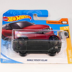 May include: Red Range Rover Velar toy car in blue and orange Hot Wheels packaging. The car is in a plastic case and the packaging has the text "Hot Wheels", "Range Rover Velar", "HW Turbo", and "hotwheels.com".