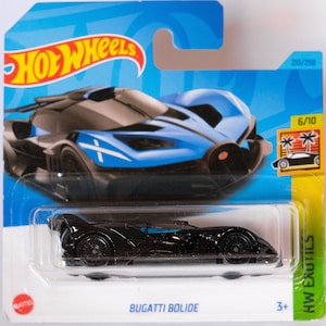 Puede incluir: Un coche de juguete negro de fundición a presión Hot Wheels, un Bugatti Bolide, en una tarjeta azul y blanca con el logotipo de Hot Wheels. El coche está en un blíster de plástico transparente. La tarjeta tiene el texto "203/250" y "6/10" en ella. La tarjeta también tiene una imagen de una palmera y un coche.