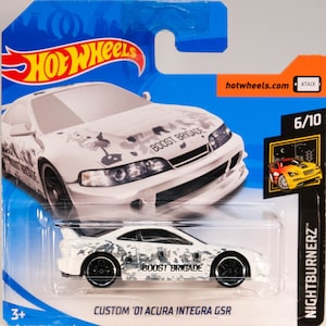 May include: White die-cast toy car model of a 2001 Acura Integra GSR with a camouflage pattern and "BOOST BRIGADE" written on the side. The car is part of the Hot Wheels Nightburnerz series.