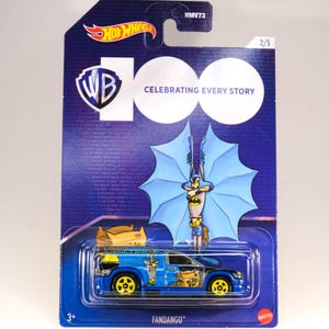 May include: A blue Hot Wheels Fandango die-cast toy car with yellow wheels, featuring a Batman theme. The packaging includes the Warner Bros. 100 logo and the text "Celebrating Every Story."