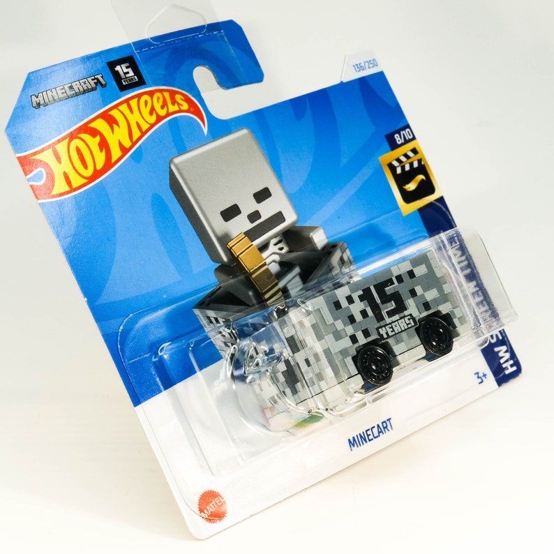 Puede incluir: Un coche de juguete Hot Wheels Minecraft 15 Years de fundici&oacute;n a presi&oacute;n con una figura de esqueleto gris que viaja en un carro de mina pixelado gris y blanco. El embalaje es azul y blanco con el logotipo de Hot Wheels y la marca Minecraft.
