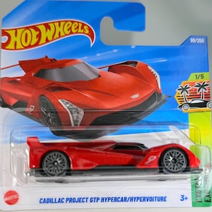 Könnte beinhalten: Ein rotes Cadillac Project GTP Hypercar Spielzeugauto. Das Spielzeugauto befindet sich in einer Verpackung mit dem Hot Wheels-Logo. Das Auto hat schwarze Räder und die Nummer 9 an der Seite. Die Verpackung enthält auch die Nummern 99/250 und 1/5.