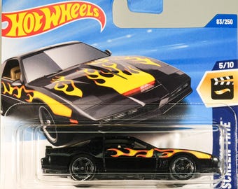 May include: A black Hot Wheels die-cast car model of the Knight Rider K.I.T.T. car. The car has yellow flames on the hood and sides. The car is in a plastic blister pack with a blue background. The package says "Knight Rider" and "Hot Wheels" on the top. The package also has a number "83/250" on the top right corner and a number "5/10" on the bottom right corner.