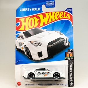 Op de afbeelding: Witte Hot Wheels-speelgoedauto met zwarte accenten en de tekst "Liberty Walk" en "HW Dream Garage" op de verpakking. De auto is een Nissan 35GT-RR Ver.2 en is genummerd 154/250.