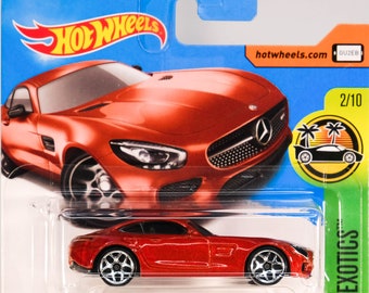 May include: A red die-cast '15 Mercedes-AMG GT toy car in a clear plastic package. The car has silver wheels and is part of the HW Exotics series. The packaging features the Hot Wheels logo and a tropical scene.