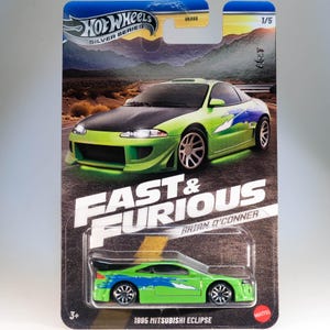 May include: A green 1995 Mitsubishi Eclipse die-cast toy car from the Fast & Furious film franchise. The car has a black bonnet and blue and white graphics on the sides. The car is packaged in a Hot Wheels Silver Series box with the Fast & Furious logo and Brian O'Conner's name.