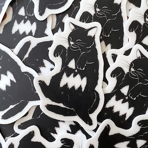 May include: A set of black and white stickers featuring a stylized illustration of a cat with a wavy pattern on its body. The cat is shown in various poses, including sleeping, sitting, and stretching.