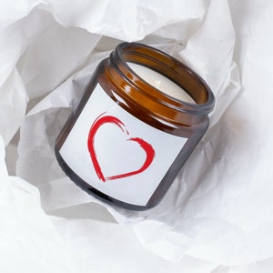 May include: A brown glass candle jar with a white label and a red heart design. The label says "Love".