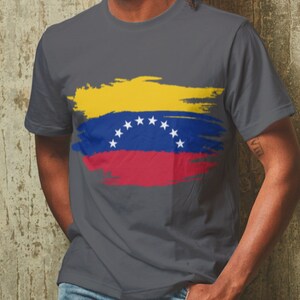 May include: A dark gray t-shirt with a yellow, blue, and red paint-splattered design of the Venezuelan flag.