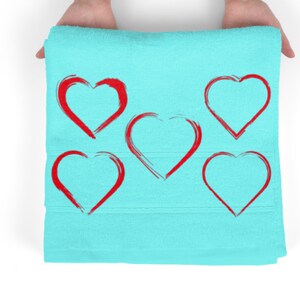May include: A light blue towel with five red heart shapes drawn on it.