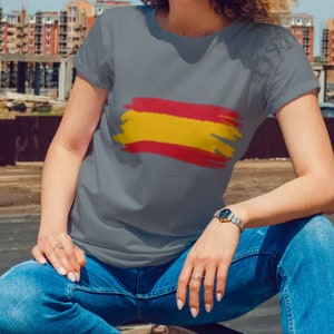 May include: A gray t-shirt with a red and yellow brushstroke design resembling the Spanish flag.