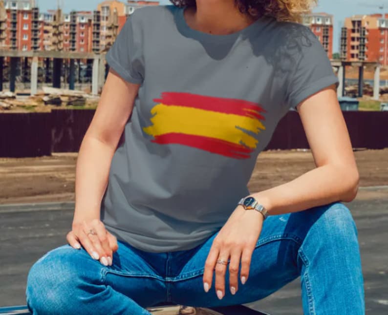 May include: A gray t-shirt with a red and yellow brushstroke design resembling the Spanish flag.