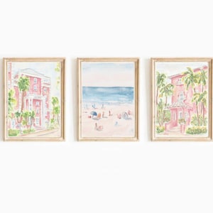 Op de afbeelding: Een set van drie aquarellen die een roze gebouw met palmbomen, een strandscene met mensen en een parasol en een ander roze gebouw met palmbomen afbeelden.
