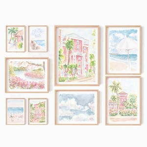 Op de afbeelding: Een verzameling ingelijste aquarel schilderijen met tropische taferelen. Het kunstwerk omvat strandgezichten, gebouwen en landschappen in zachte pastelkleuren. Elk stuk is gevat in een natuurlijke houten lijst, wat een samenhangende galerijwand creëert.