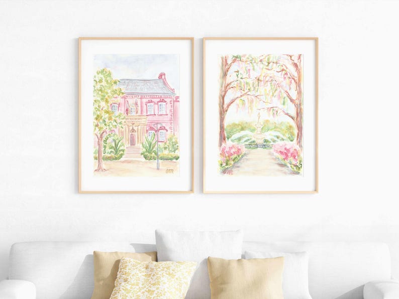 May include: Two watercolor paintings in wooden frames. The first painting shows a pink house with a green tree in front. The second painting shows a path leading to a fountain with trees and flowers on either side.