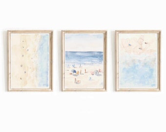 Puede incluir: Tres acuarelas enmarcadas que representan una escena de playa. La primera pintura muestra una vista desde arriba de una playa de arena con agua azul. La segunda pintura muestra una playa con gente y sombrillas. La tercera pintura muestra un primer plano de las olas del océano.