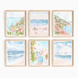 以下が含まれることがあります： 海岸の町のさまざまなシーンを描いた水彩画6点セット。絵画には、ドームのある教会、人々のいるビーチ、青いドアのある家、傘のあるビーチが描かれています。