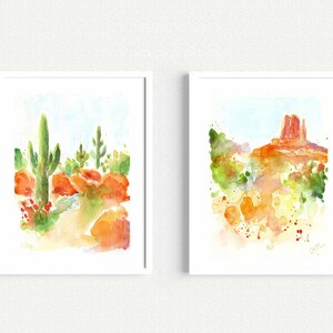 May include: Two watercolor paintings of desert landscapes. The first painting shows a tall cactus with smaller cacti and red rocks. The second painting shows a red rock formation with green bushes and a blue sky.