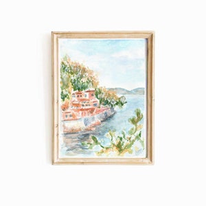May include: Watercolor painting of a red building on a cliff overlooking a blue body of water. The building is surrounded by green trees and bushes. The water is calm and reflects the sky.