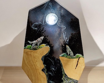 Puede incluir: Una pieza de arte de resina negra y madera con una luna y dos lobos silueteados contra un cielo nocturno estrellado.