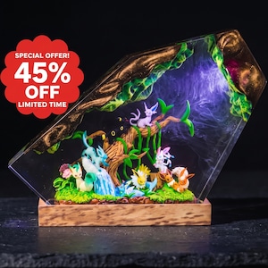 May include: A clear resin diorama featuring multiple small colorful creature figurines arranged around a central tree structure. The scene includes green foliage, a blue waterfall, and purple smoke effects, all mounted on a rectangular wooden base.