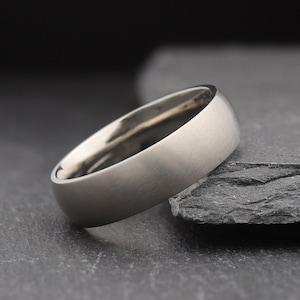 May include: A brushed silver wedding band with a rounded edge.