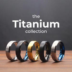 Può includere: La collezione Titanium presenta cinque anelli in titanio diversi. Gli anelli sono di vari colori, tra cui argento, nero, oro e blu.